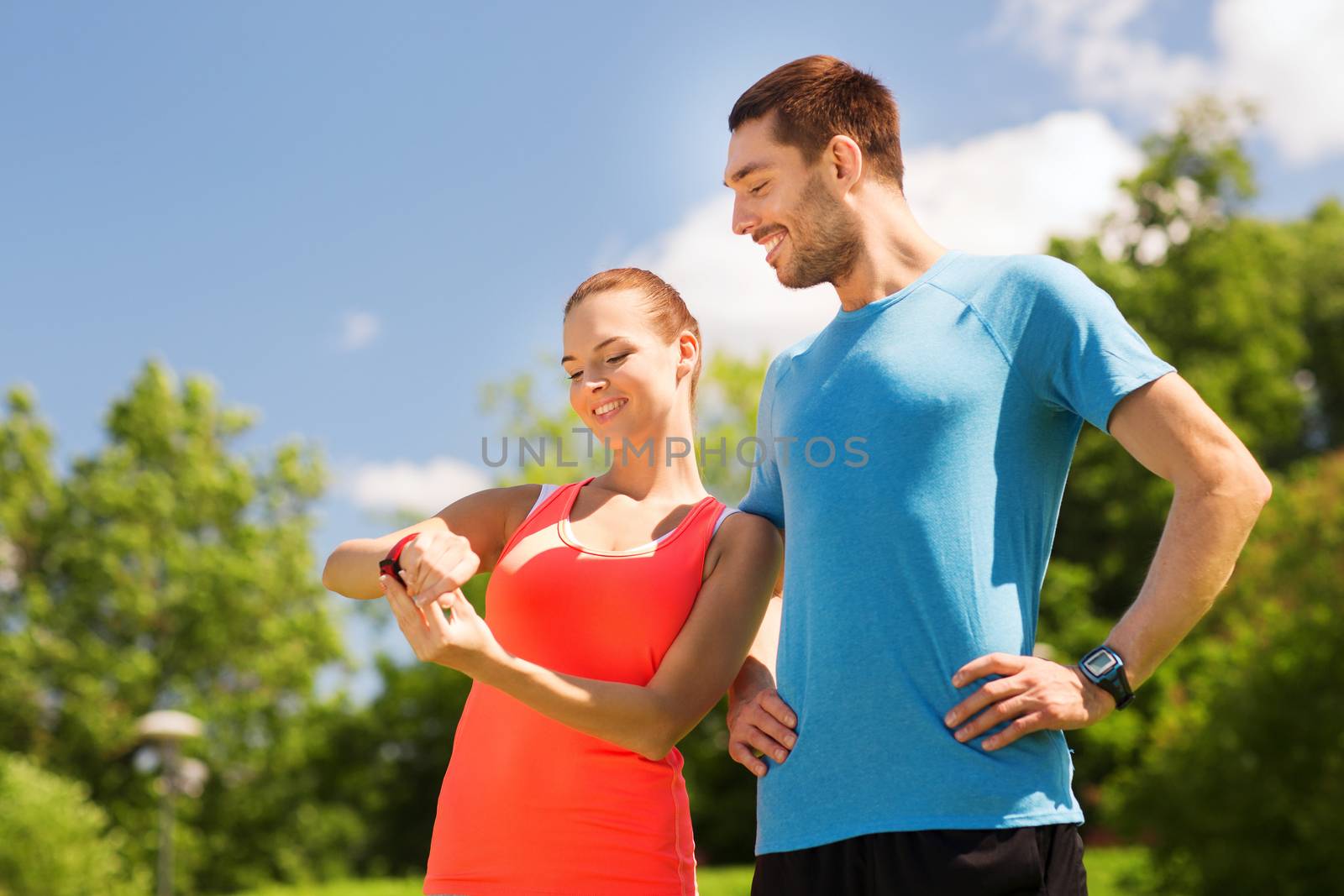 smiling people with heart rate watches outdoors by dolgachov