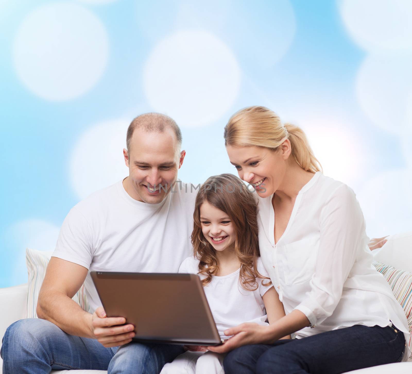 family, childhood, holidays, technology and people concept - smiling family with laptop computer over blue lights background