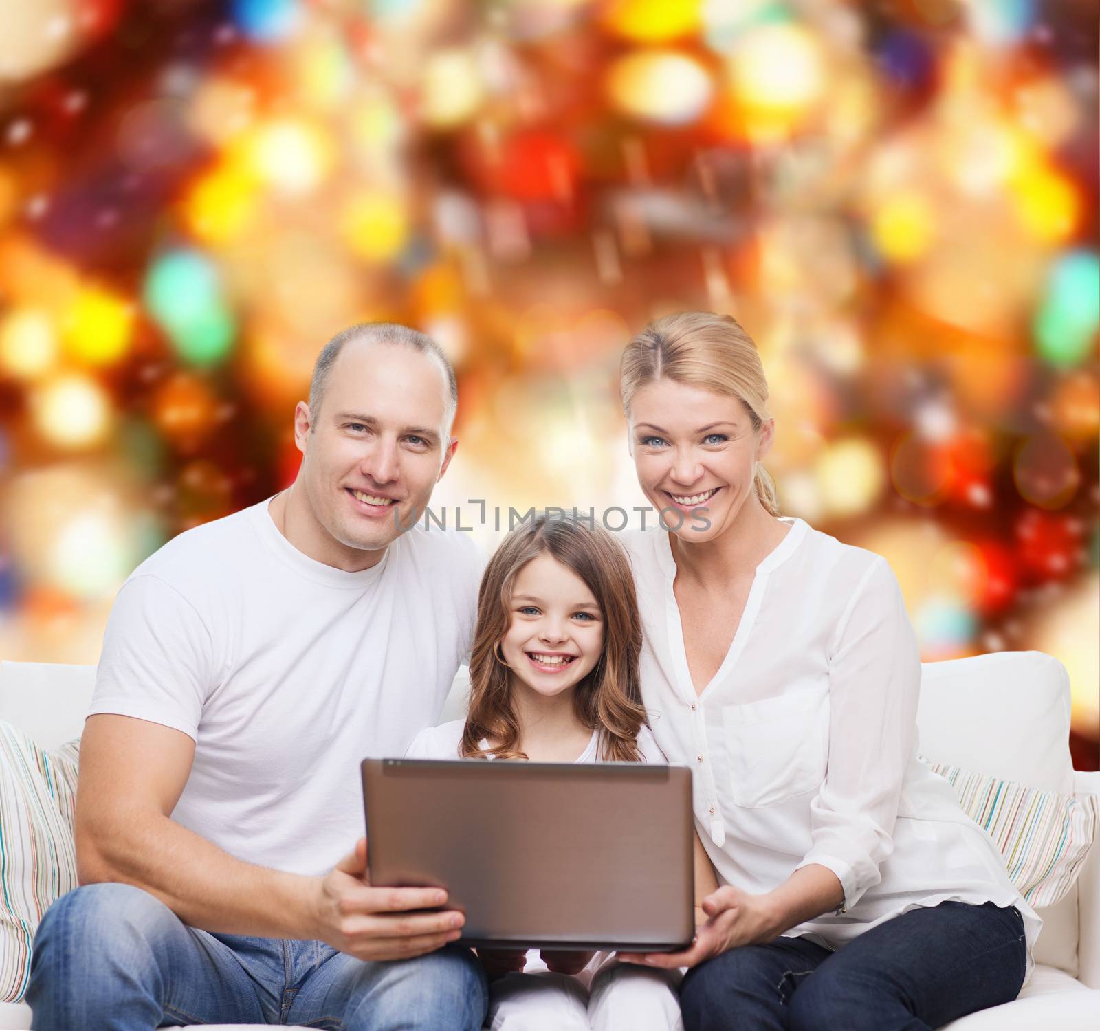 family, childhood, holidays, technology and people concept - smiling family with laptop computer over red lights background