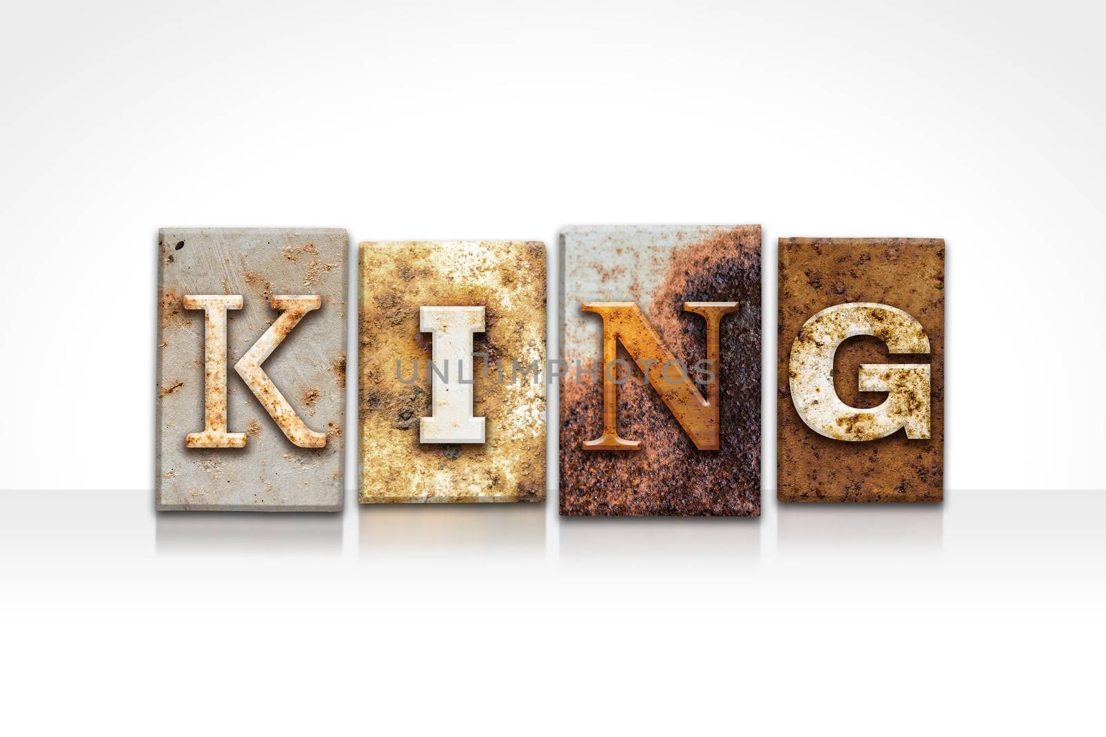 The word "KING" written in rusty metal letterpress type isolated on a white background.