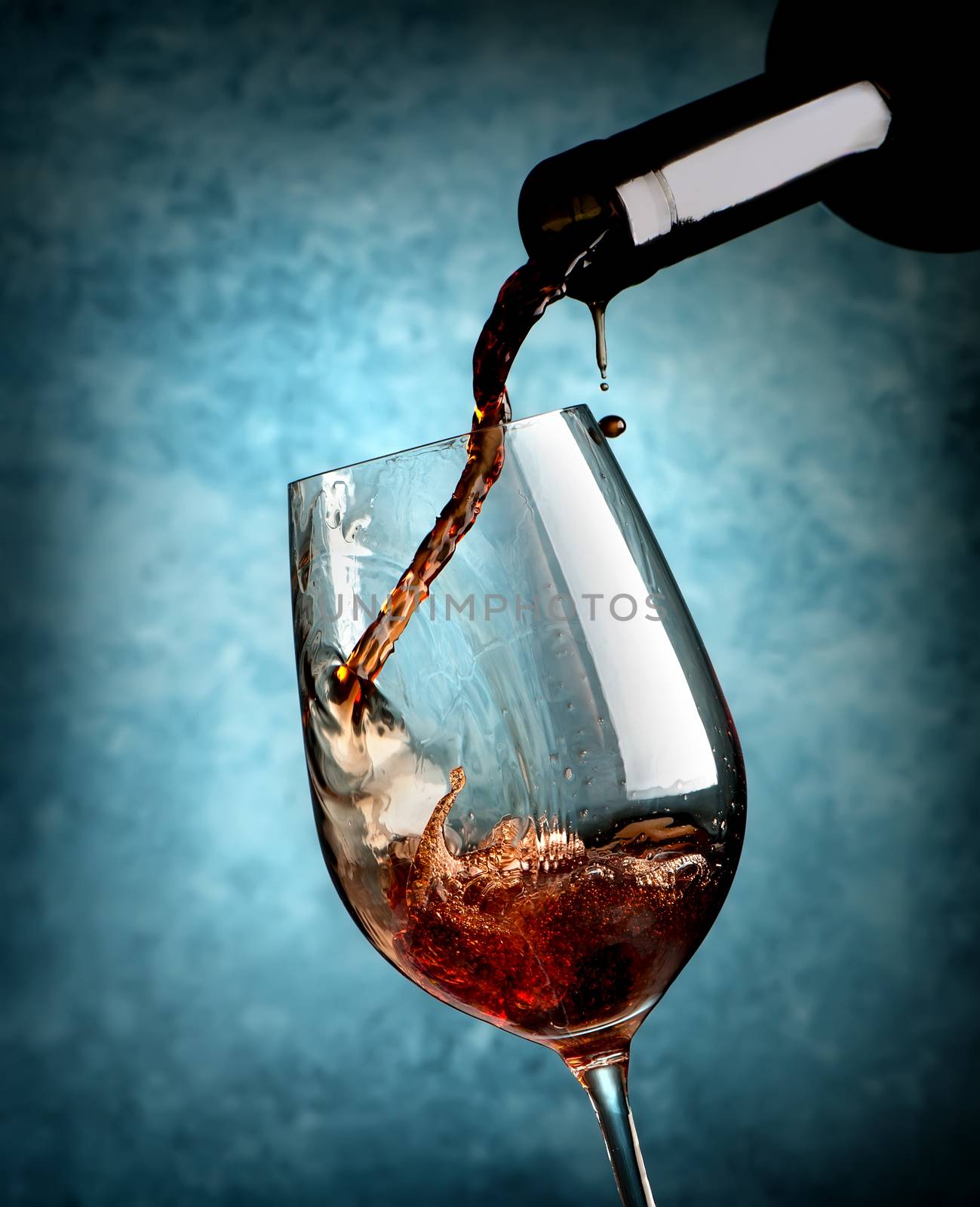 Wine pouring in wineglass on a blue background