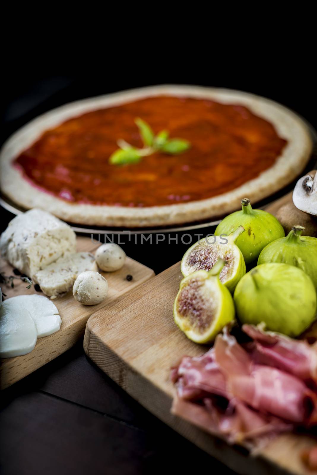 Rustic home made pizza on wooden table with fresh ingredients and cheese