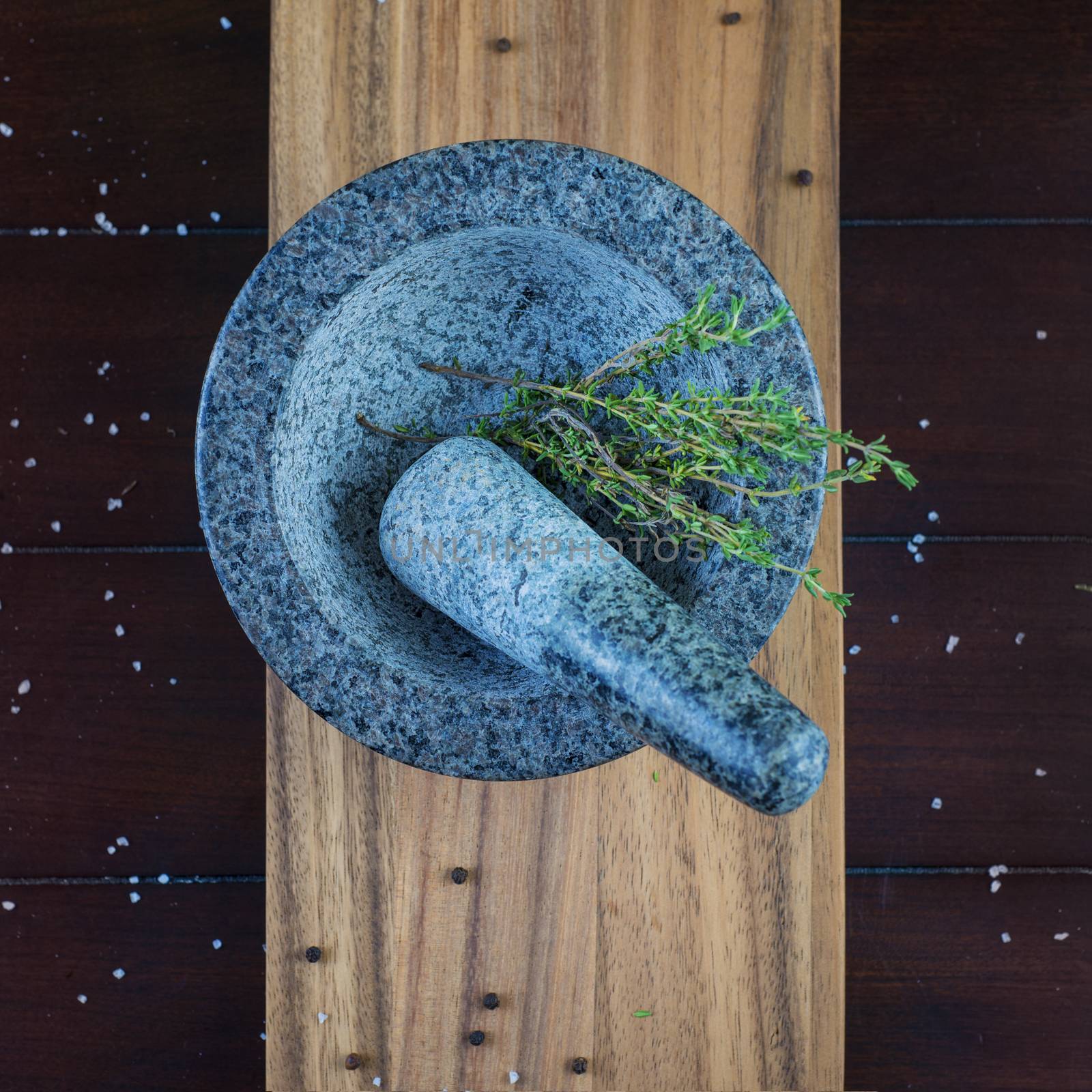 Granite stone mortar and thyme herb over wooden plank