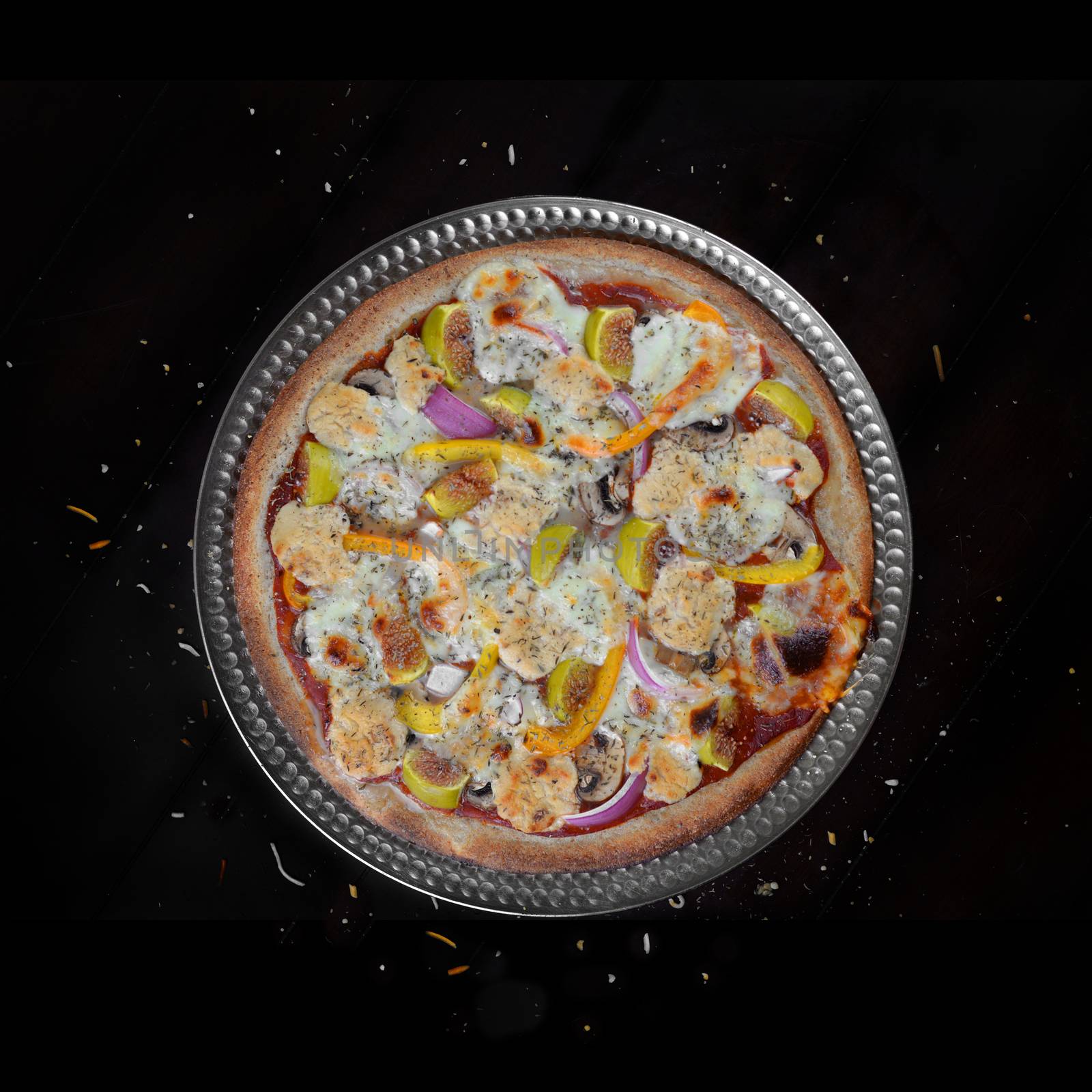 Fresh baked home made veggie pizza with figs and feta cheese over black background