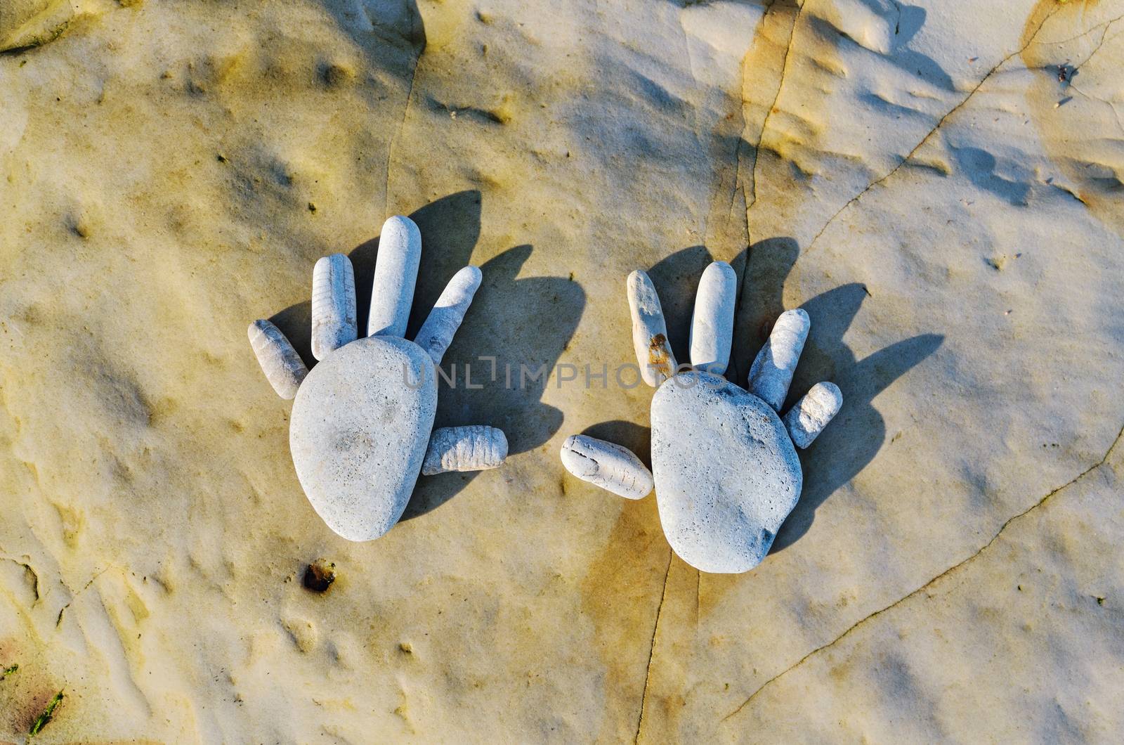 Hands of pebbles on the sea boulder