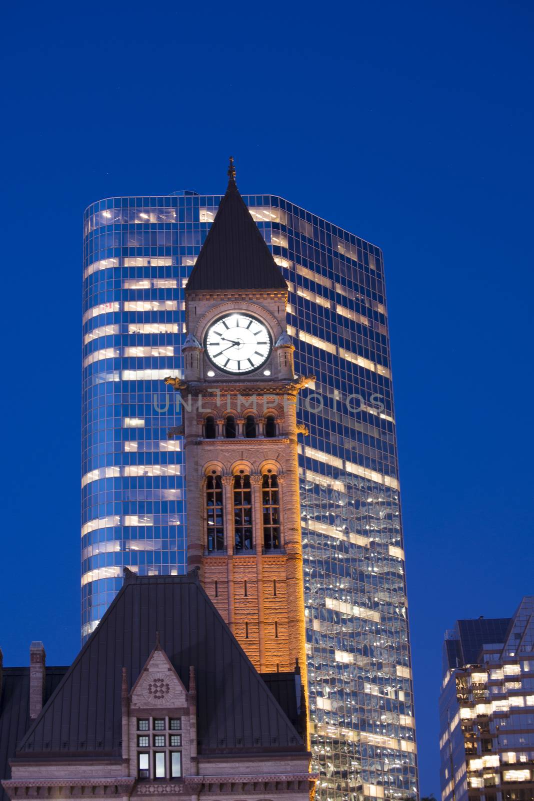 Detail of Toronto's city hall tower clock at dusk against modern building