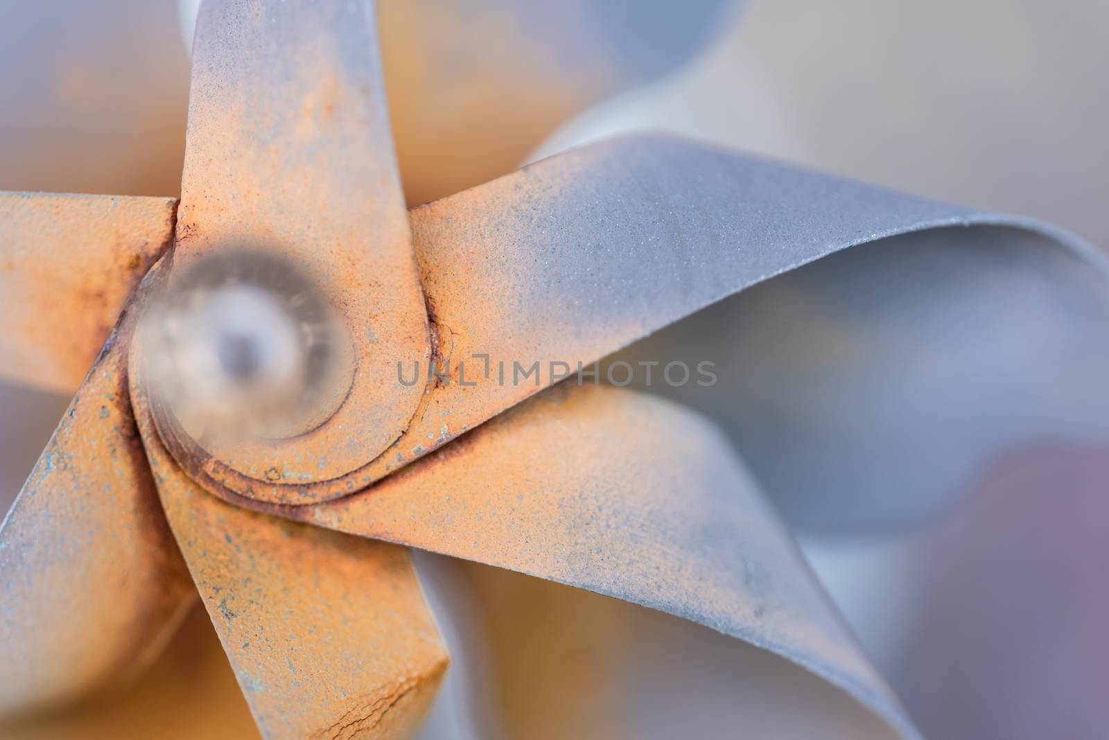 A macro shot of a decorative pinwheel garden ornament made of rusted metal.