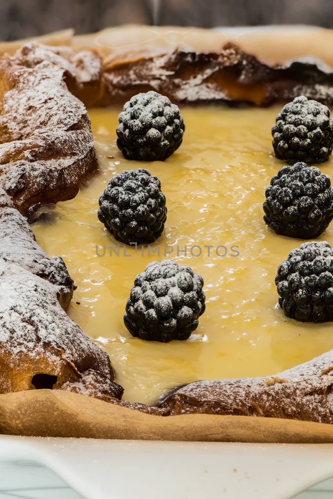 eclair cake in casserole dish with blackberry on wood table