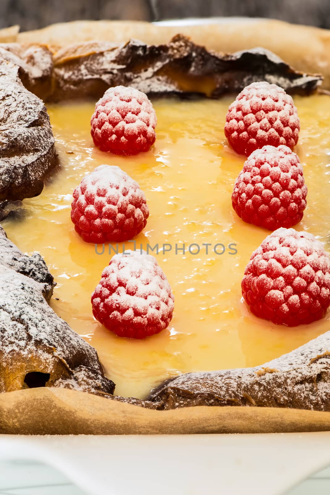 eclair cake in casserole dish with raspberry on wood table