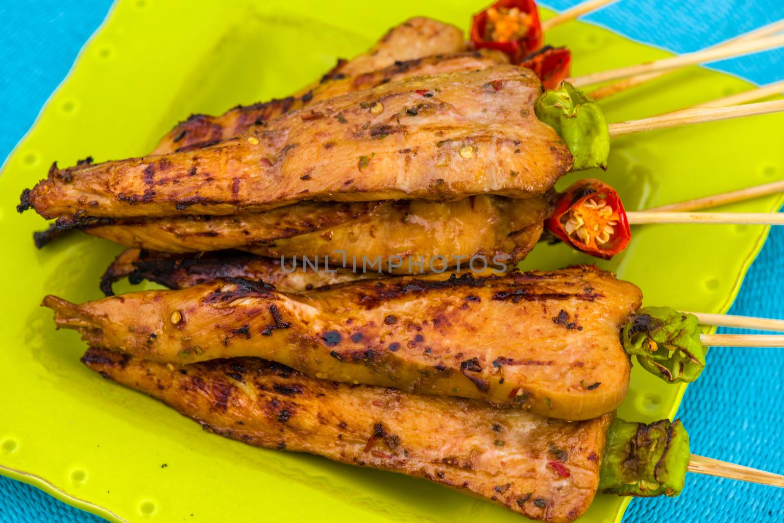 chicken skewers on green plate decorated with red and green pepper