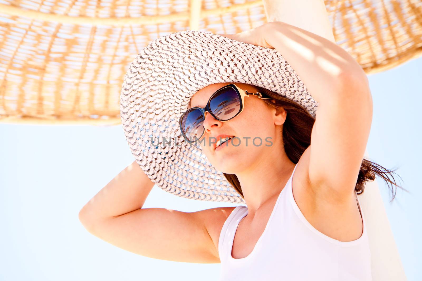 A young pretty woman holding her hat on the beach