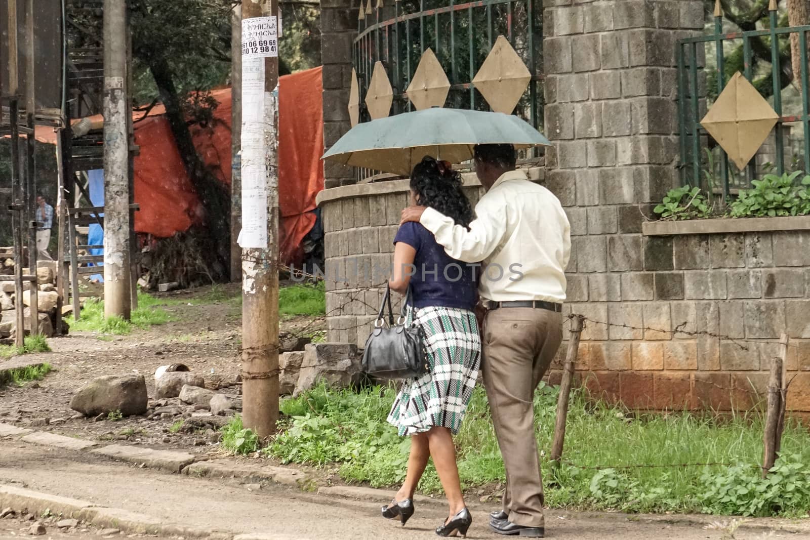 A couple walking on the streets of Addis with an umbrella by derejeb