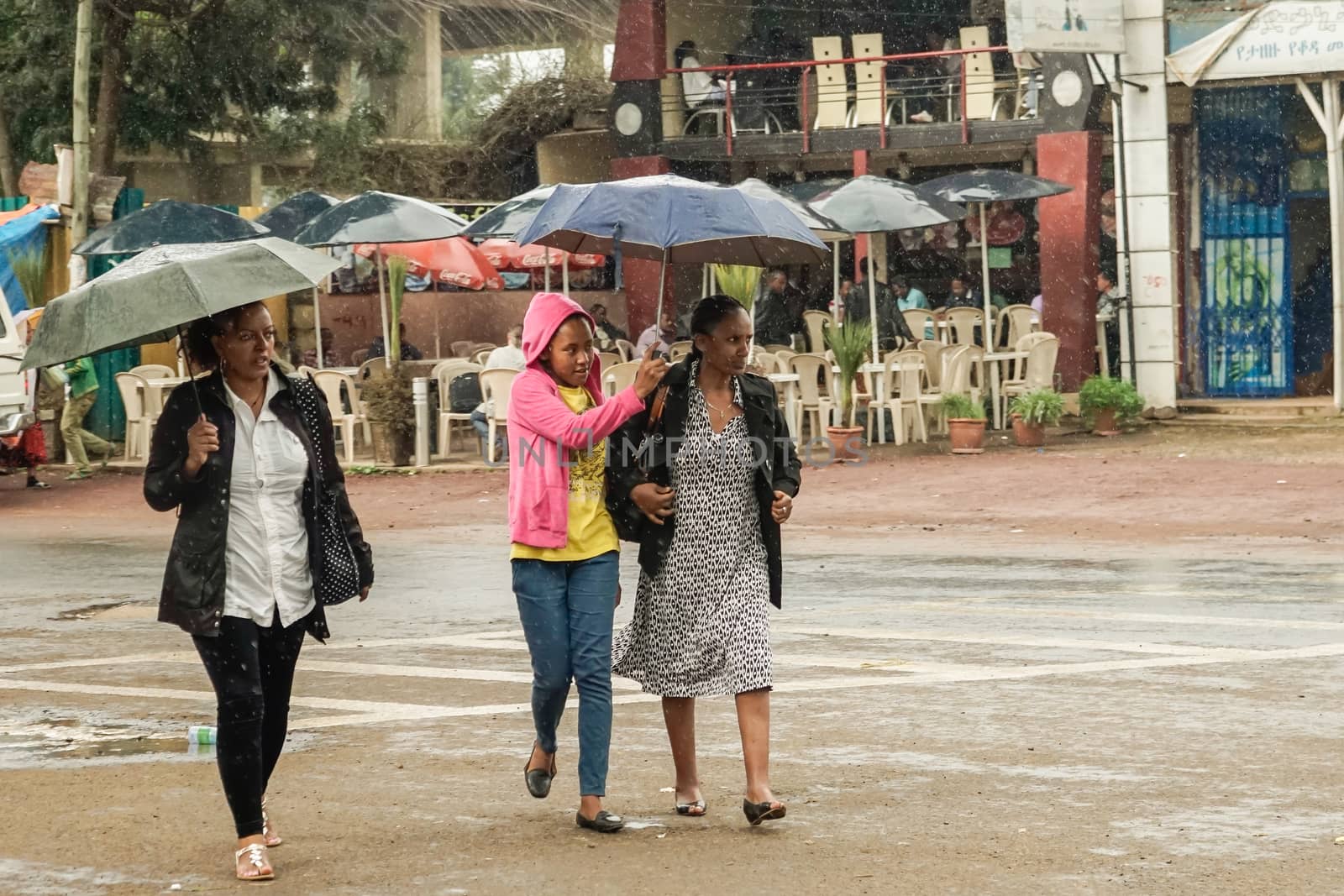 Addis Ababa - July 26: Three women with an umbrella walk on the streets of Addis in the rain on June 26, 2015 in Addis Ababa, Ethiopia.