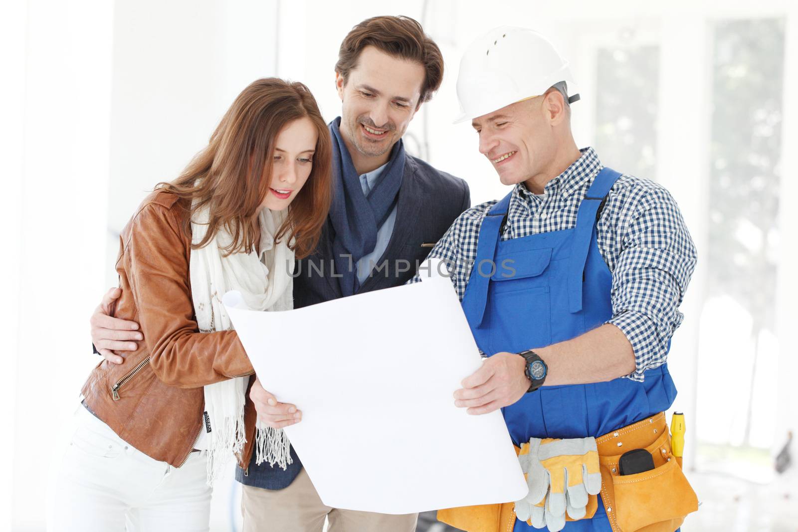 foreman shows house design plans to a young couple