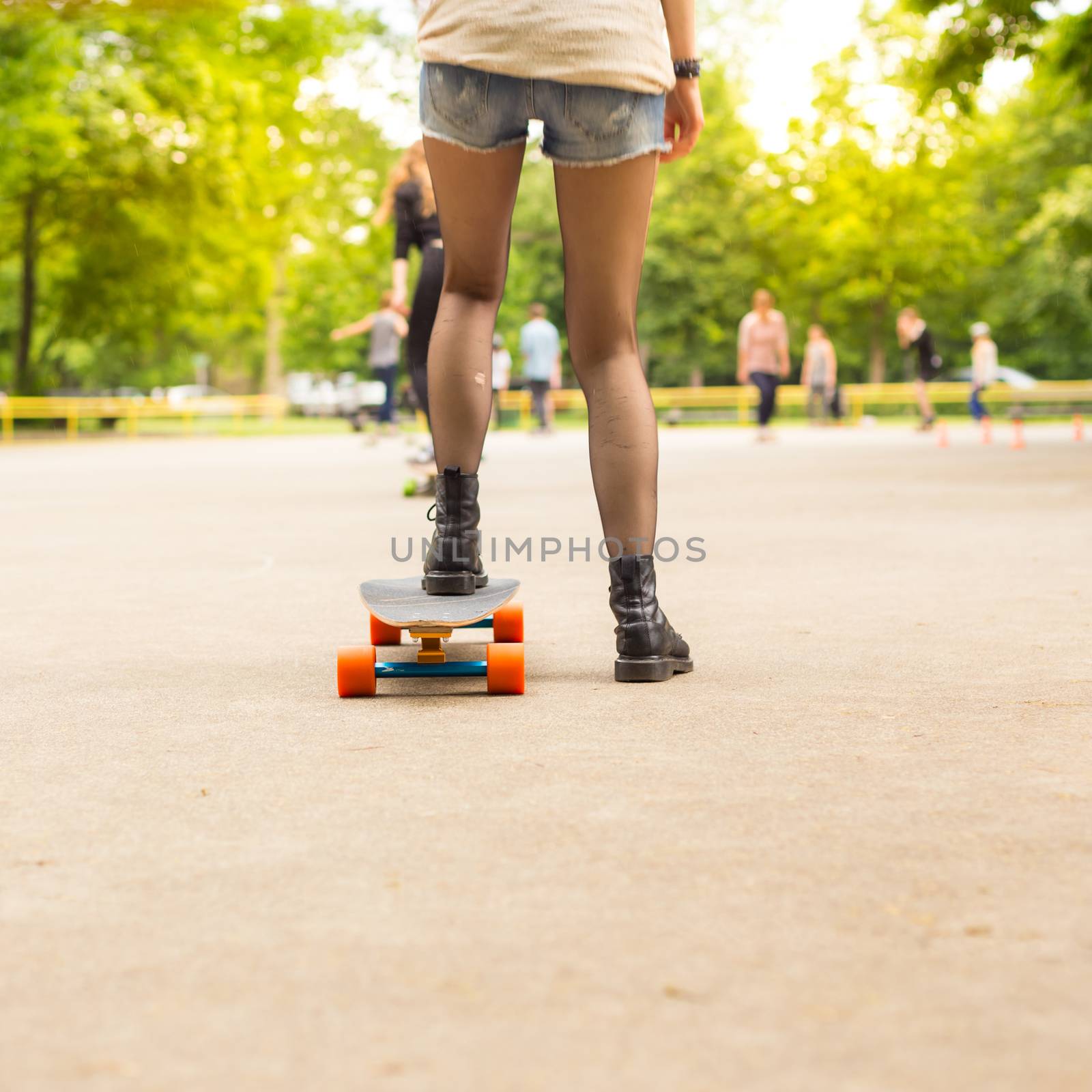 Teenage girl wearing black boots and stockings practicing long board riding outdoors in skateboarding park. Active urban life. Urban subculture.