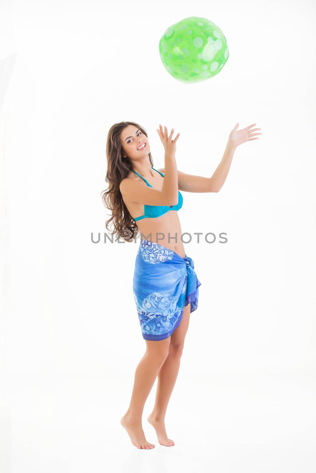 Young beautiful woman plays with a ball on isolated studio bakground
