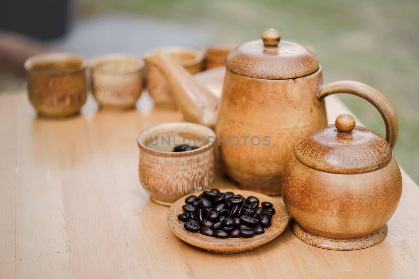 Coffee beans, cup of coffee and teapot on wooden desk. Set of cafe