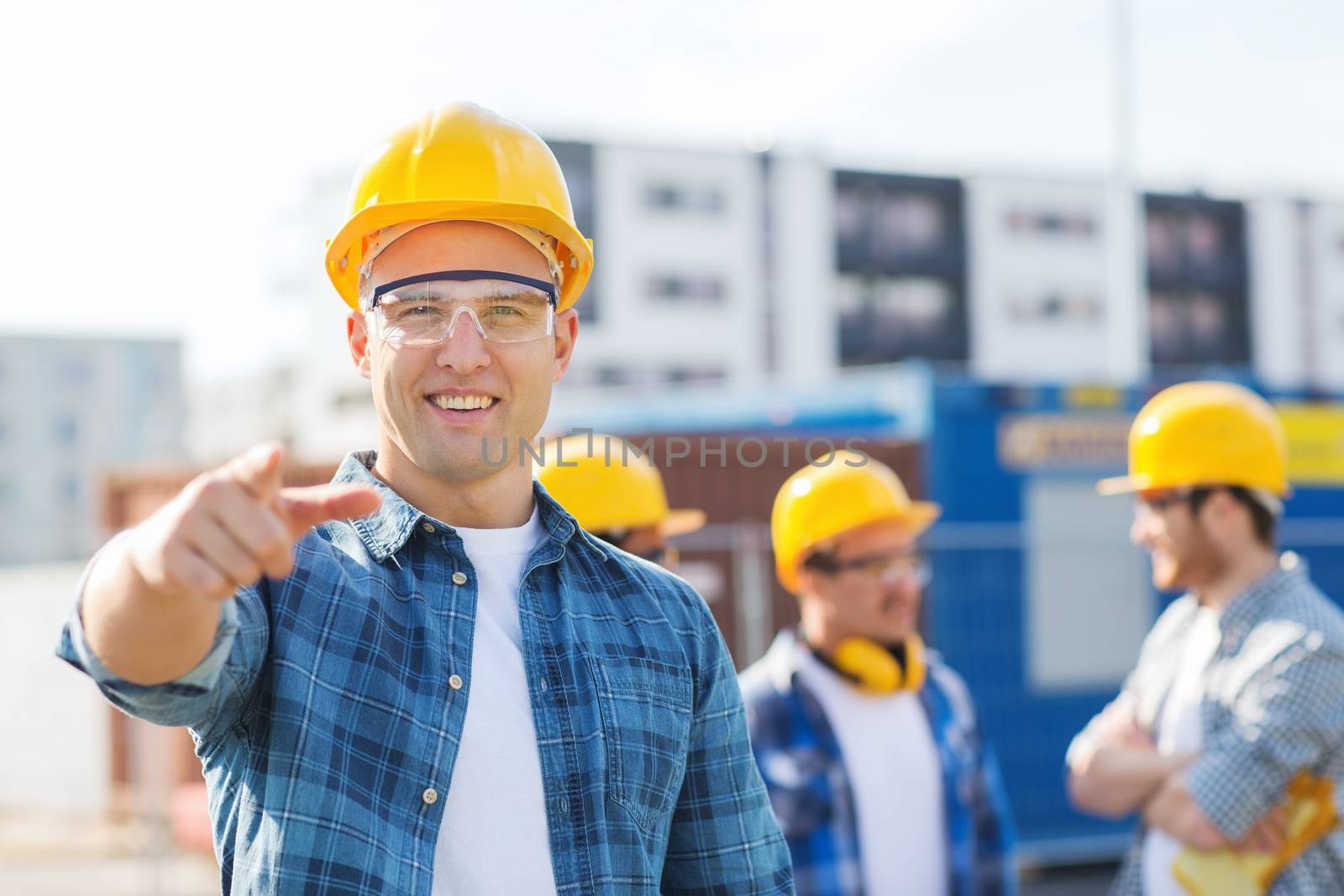 group of smiling builders in hardhats outdoors by dolgachov