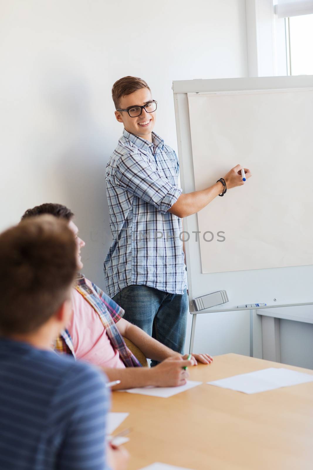 education, teamwork and people concept - smiling students with white board sitting at table indoors