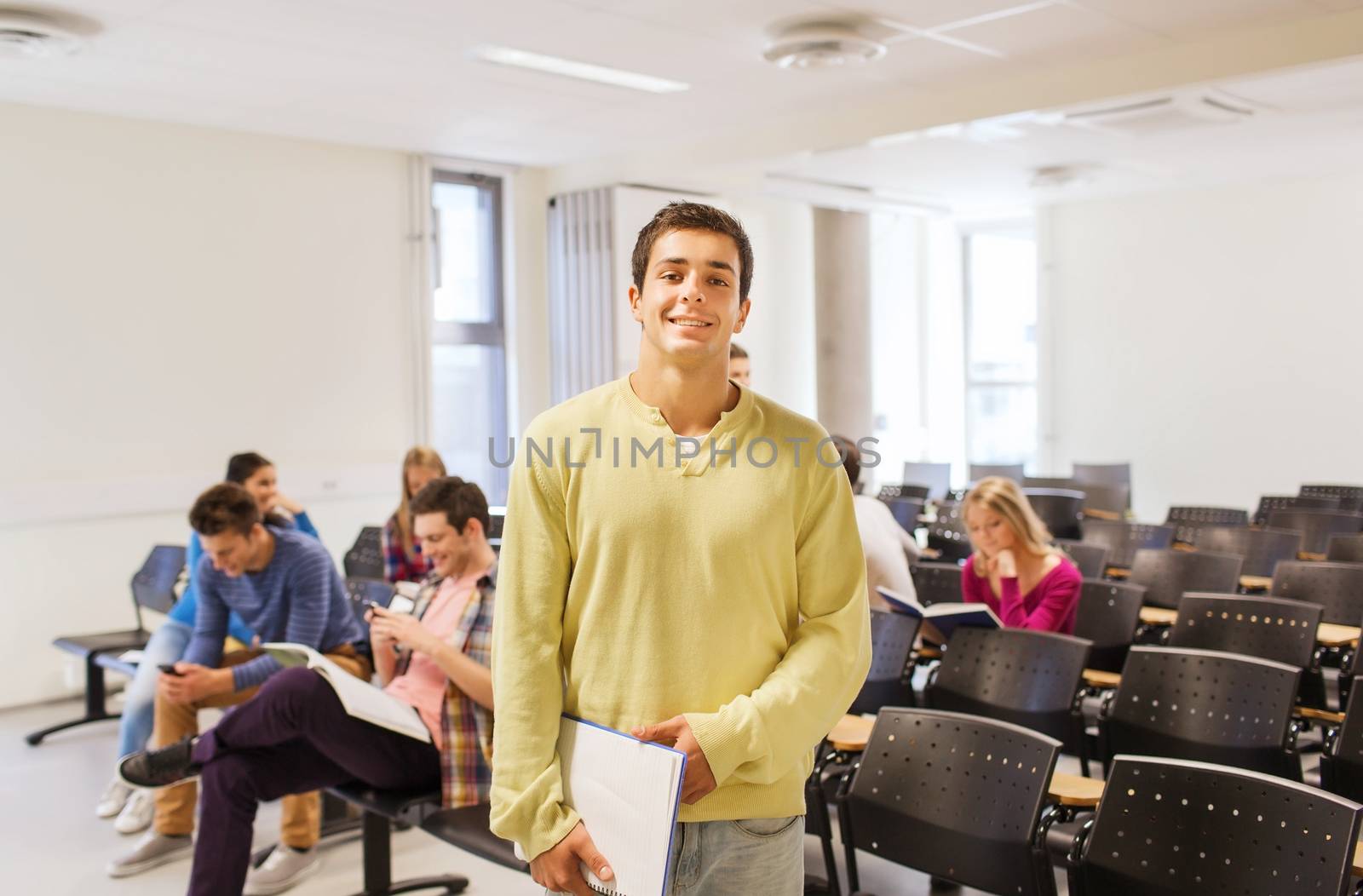 education, high school, teamwork and people concept - group of smiling students with notepads sitting in lecture hall