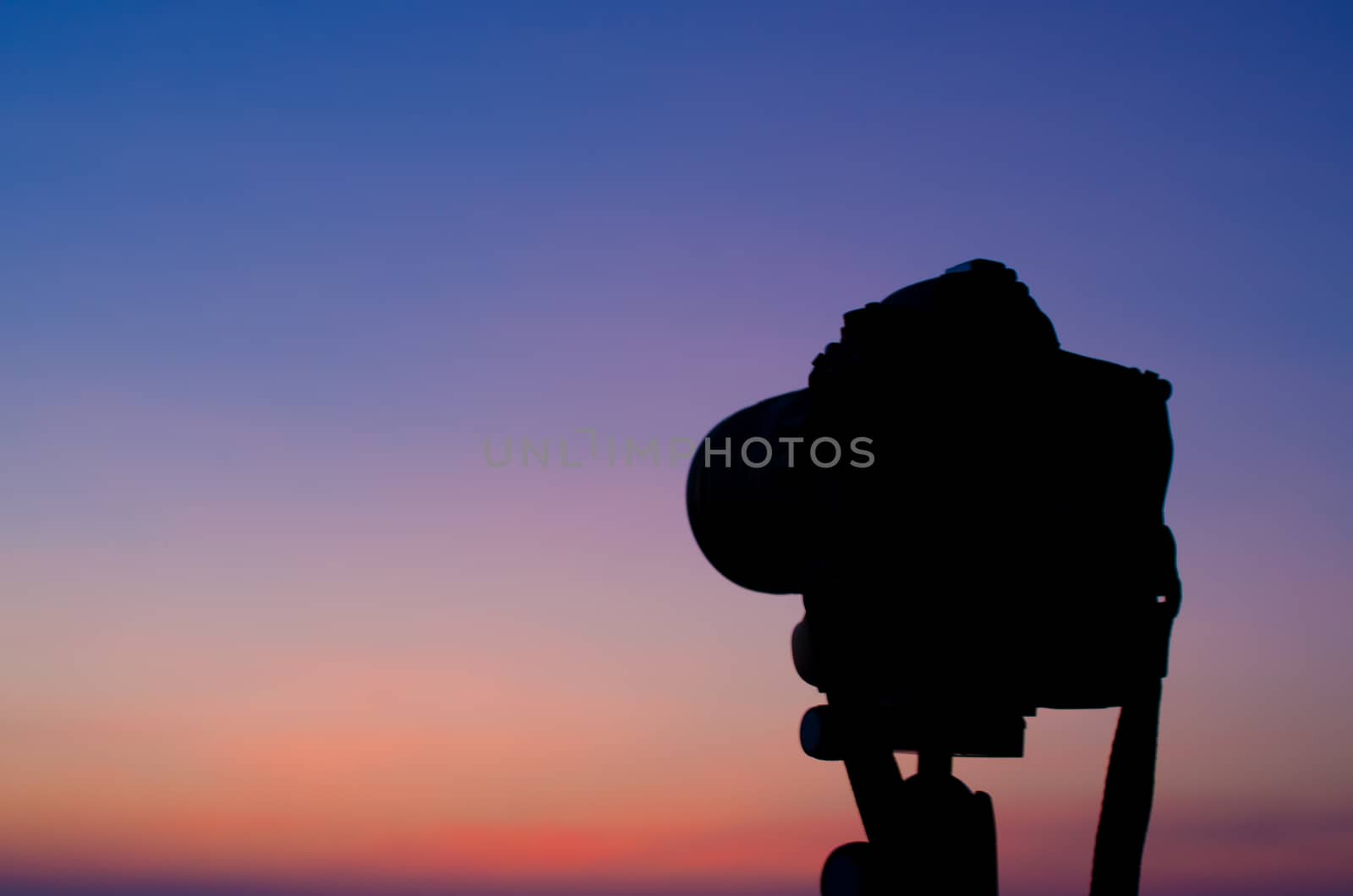 Silhouette of DSLR camera at sea with sunset sky by pixbox77
