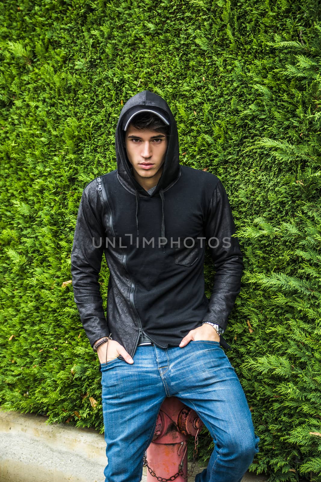 Handsome young man in black hoodie sweater standing outdoor by artofphoto