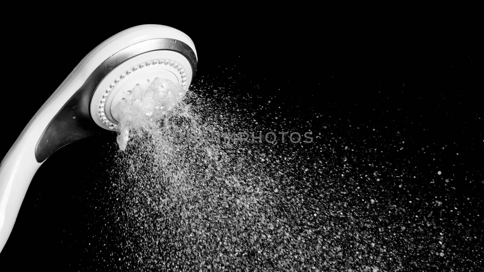 Modern shower head with running water isolated on black background