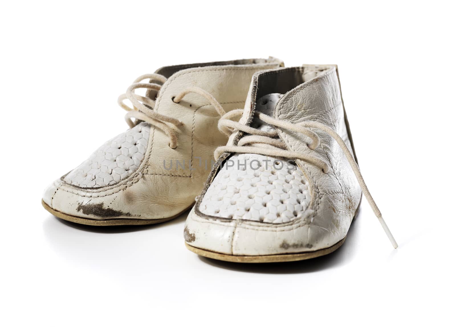 Old worn vintage leather white baby shoes isolated on white with natural shadows.