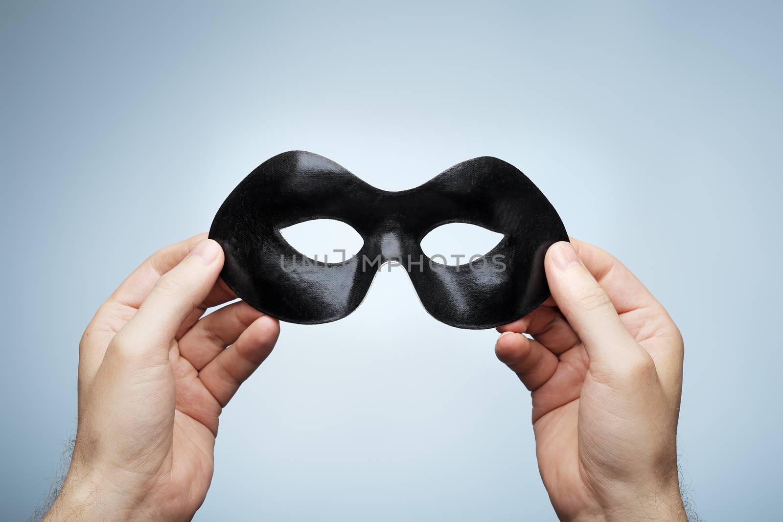 Man holding a black eye mask in his hands.