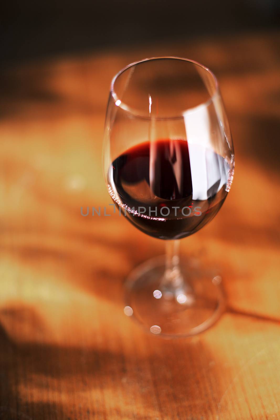 Glass of red wine on old wooden table. Very short depth of field.