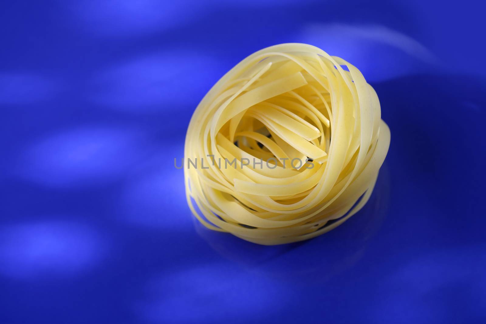 Uncooked pasta tagliatelle on a blue plate