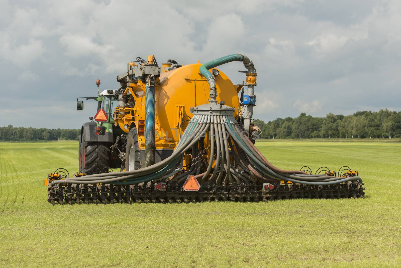 Agriculture, injecting of liquid manure with tractor and yellow vulture spreader trailer