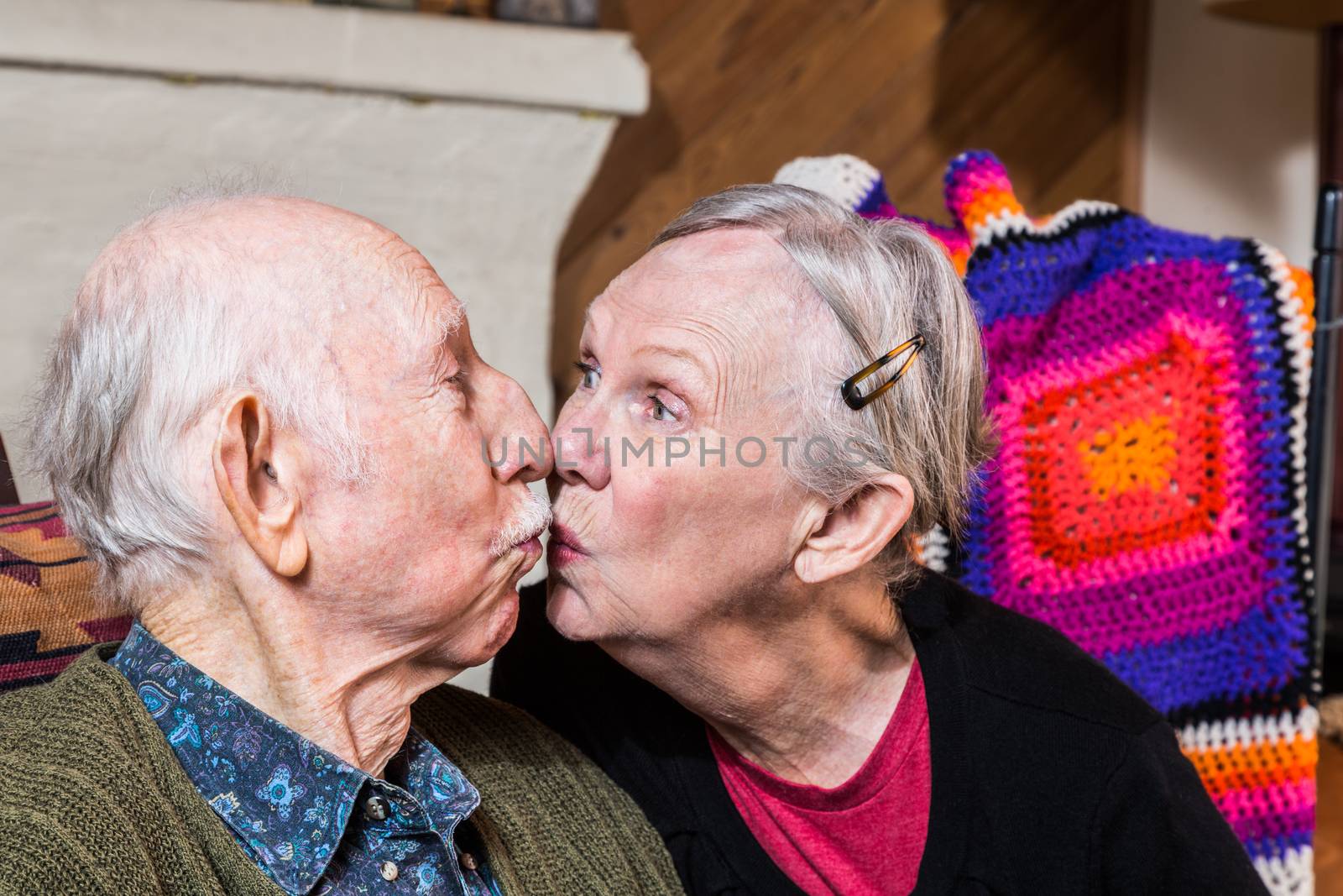 Happy elderly couple sitting in livingroom kissing