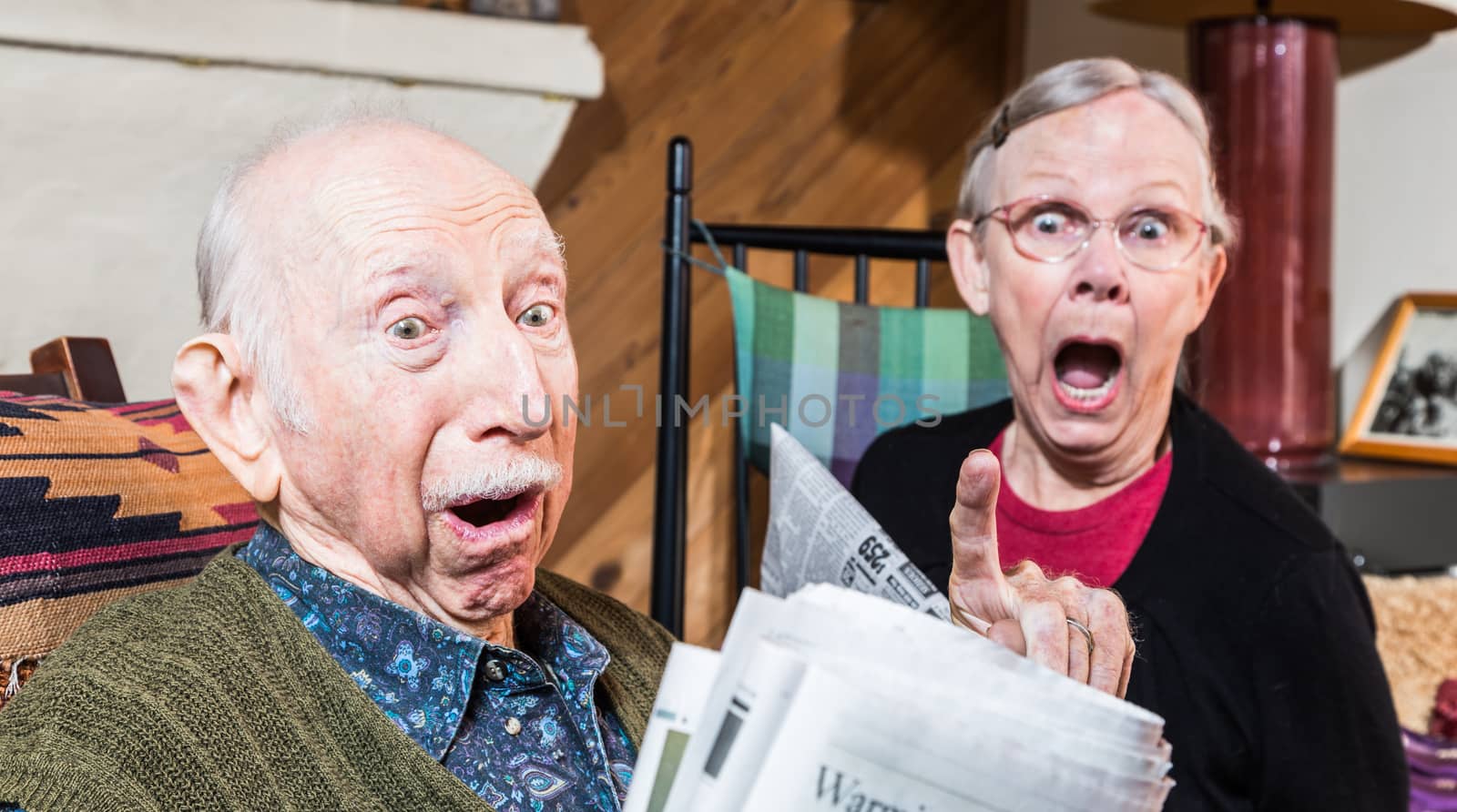 Angry older couple reading newspaper in living-room