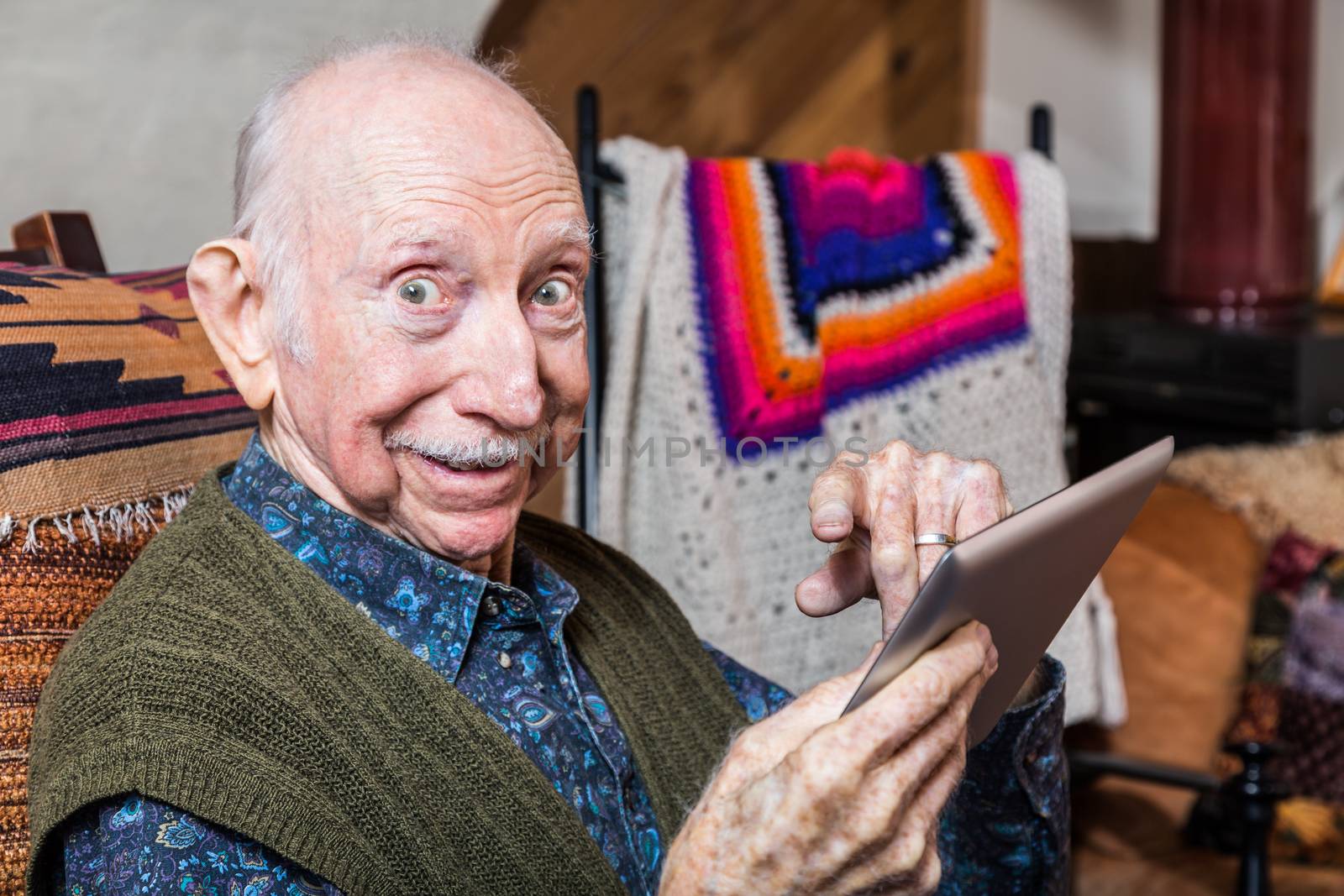 Elder gentleman working on a tablet in his living-room