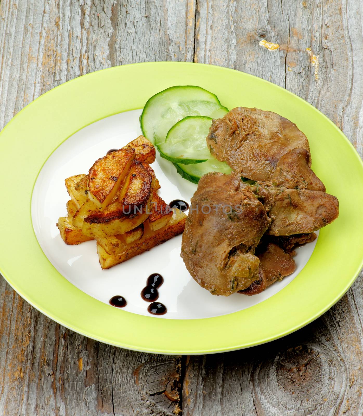 Delicious Roasted Chicken Liver Arranged with Grilled Potato Sticks, Cucumber and Balsamic Sauce on Green Plate Cross Section on Rustic Wooden background