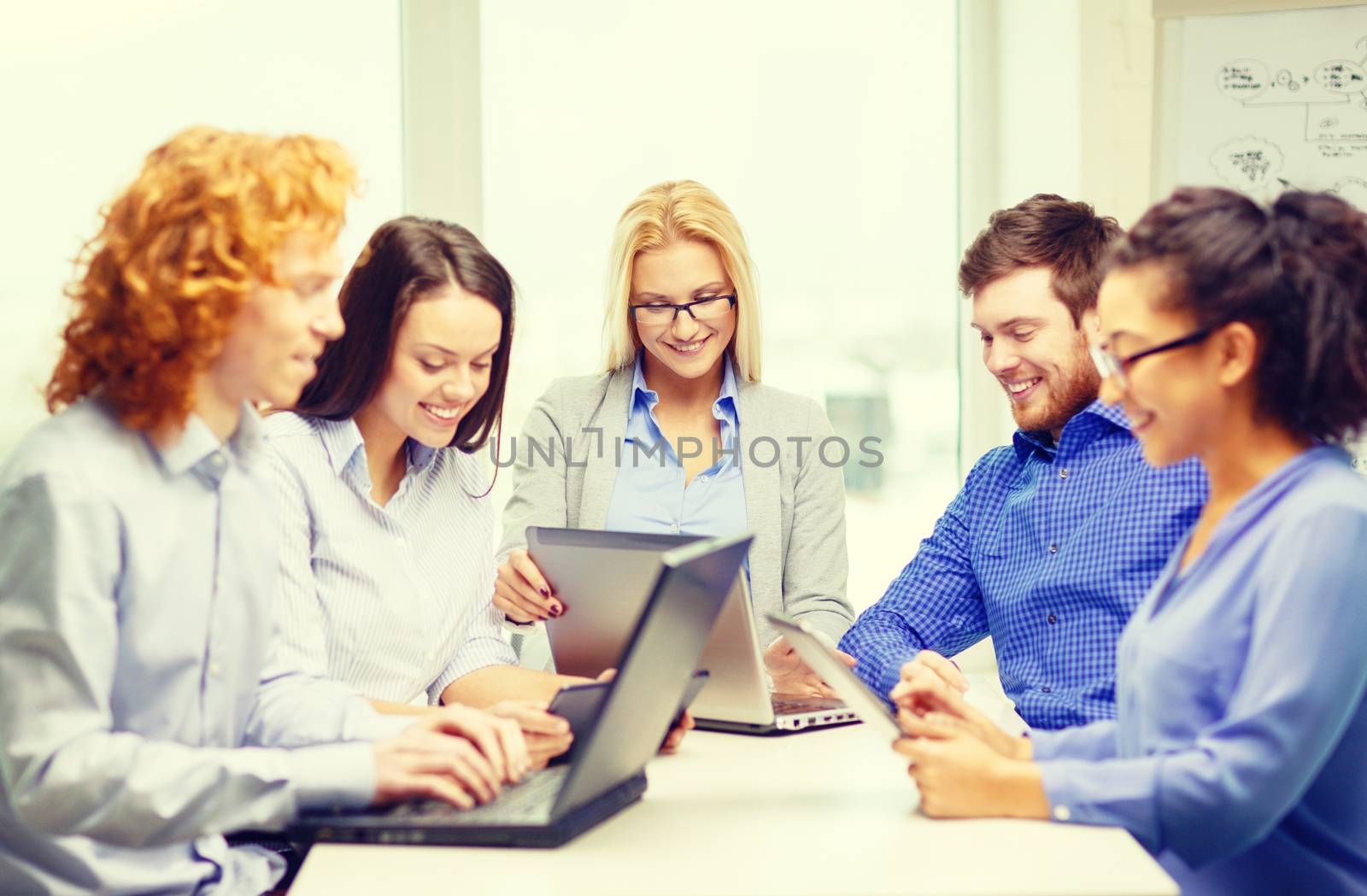 business, office and startup concept - smiling creative team with table pc and laptop computers working in office