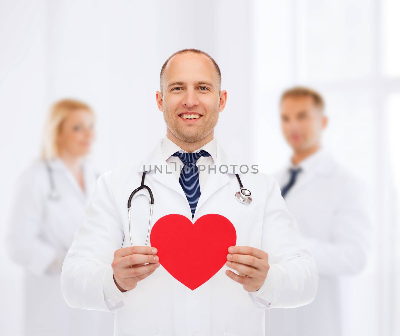 medicine, profession, charity and healthcare concept - smiling male doctor with red heart and stethoscope over group of medics