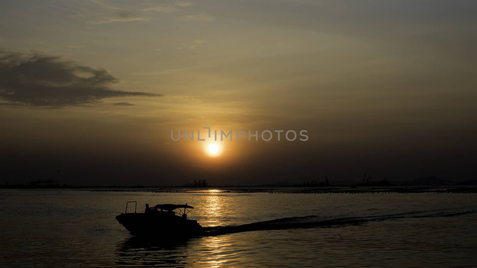 Speed boat silhouette in sea with sunset sky background