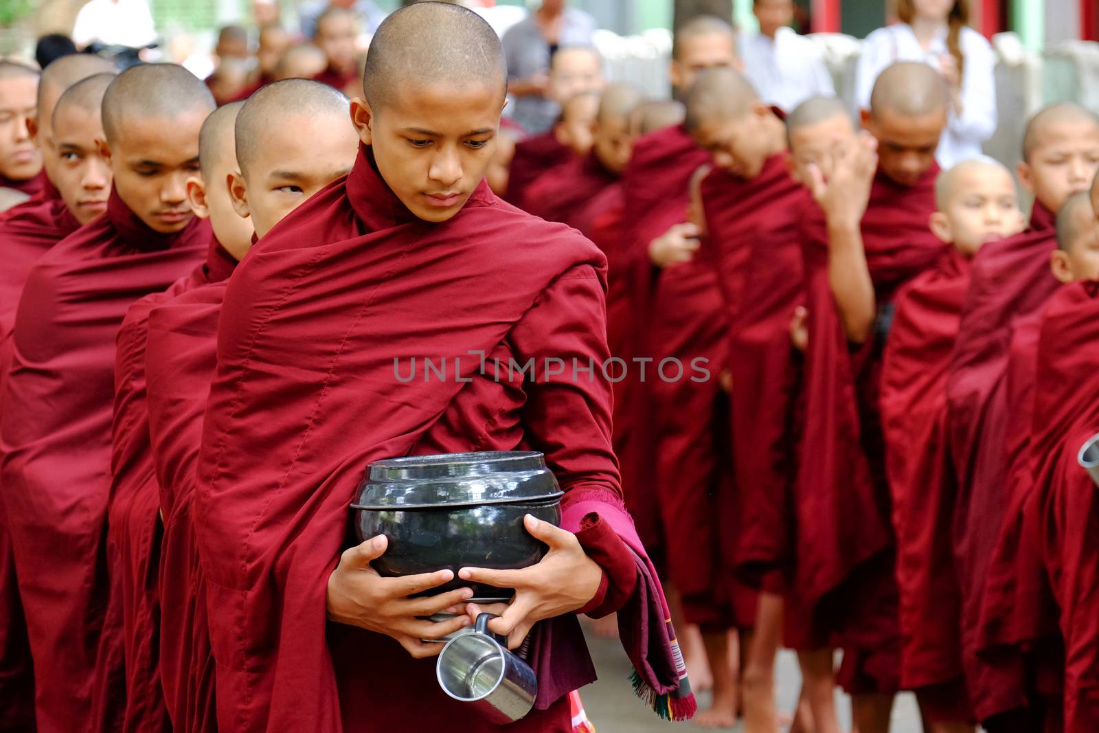 MYANMAR, AMARAPURA - JUNE 28, 2015: Buddhist monks queue for lunch in front of Mahagandayon monastery on 28 June 2015 in Amarapura.