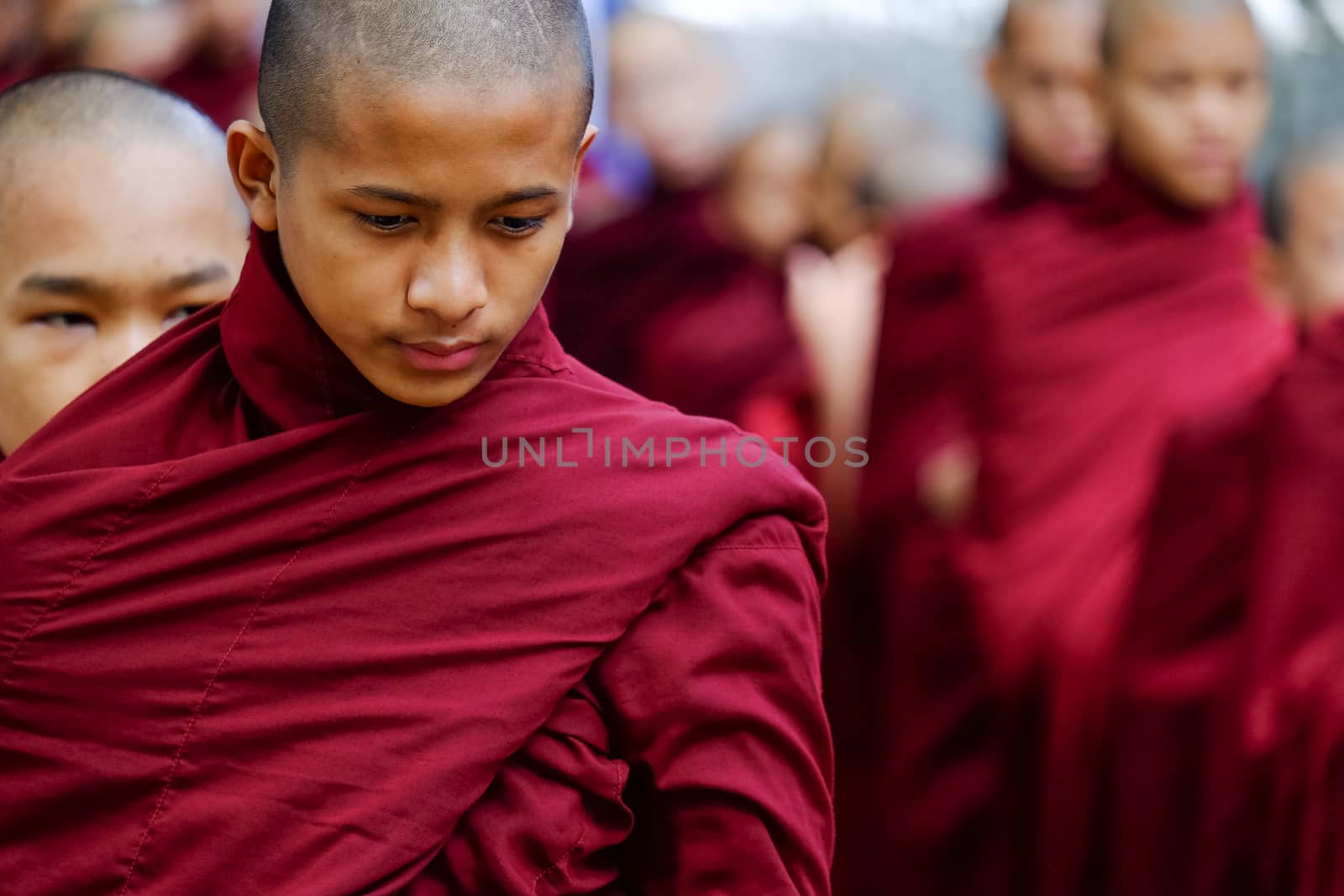 AMARAPURA, MYANMAR - JUNE 28, 2015: Buddhist monks queue for lunch by martinm303