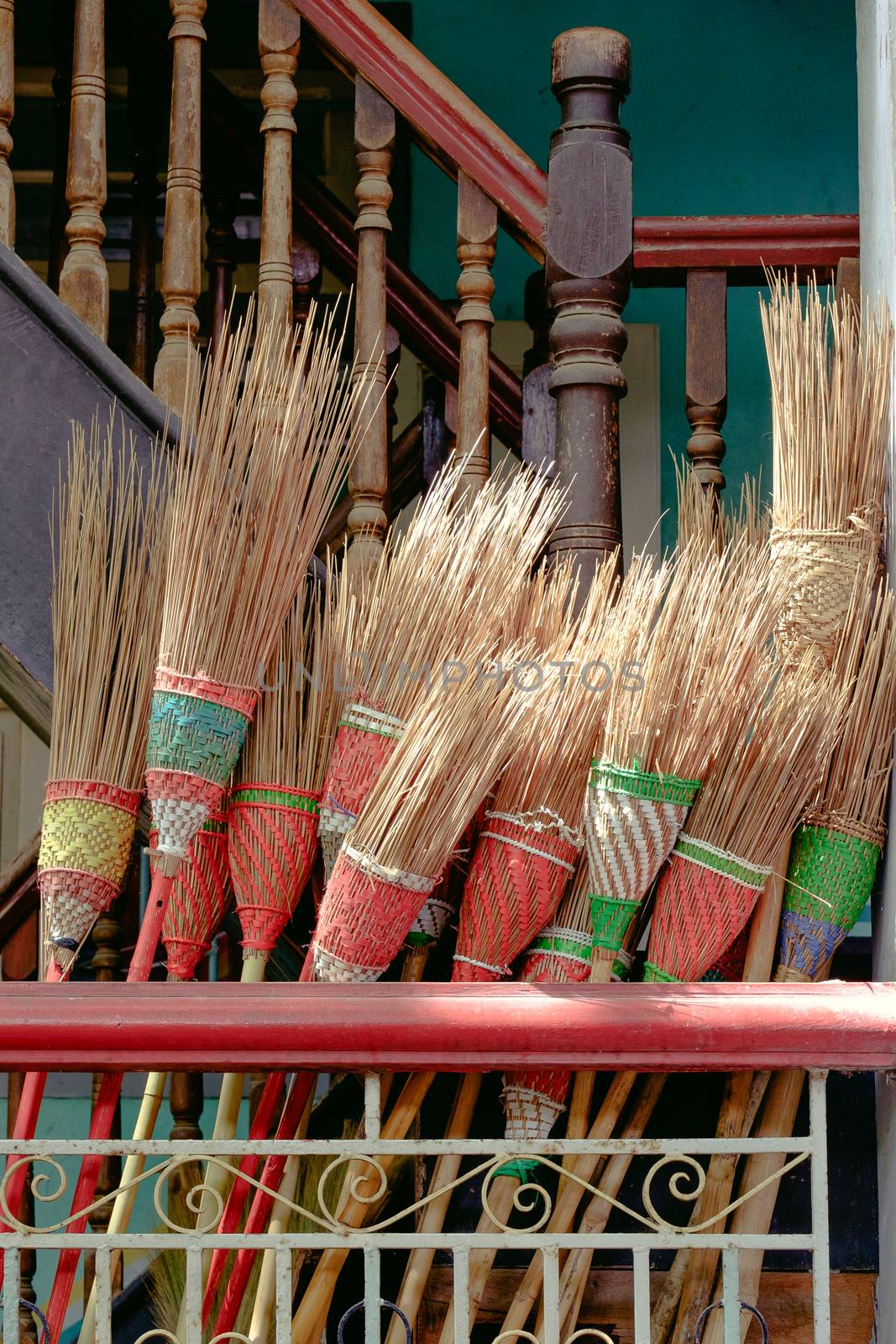 Detail of colorful rustic brooms in wooden stairway by martinm303