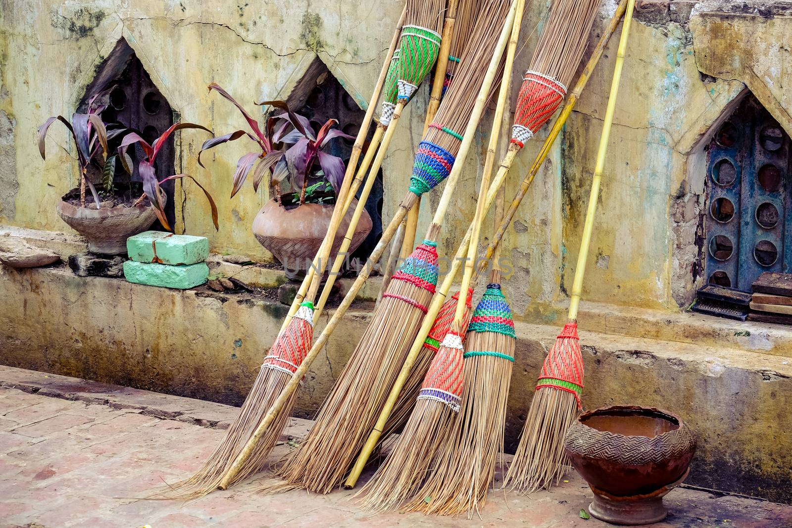 Detail of colorful rustic brooms in vintage style against weathered wall