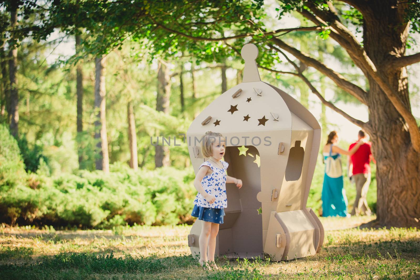 girl playing in cardboard spaceship in a city park on a sunny day