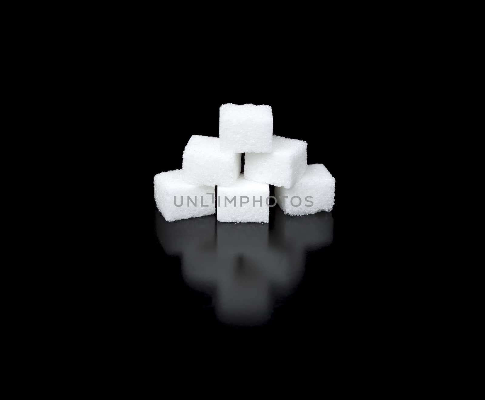 Sugar Cubes in a Pyramid with completely black background and reflection.