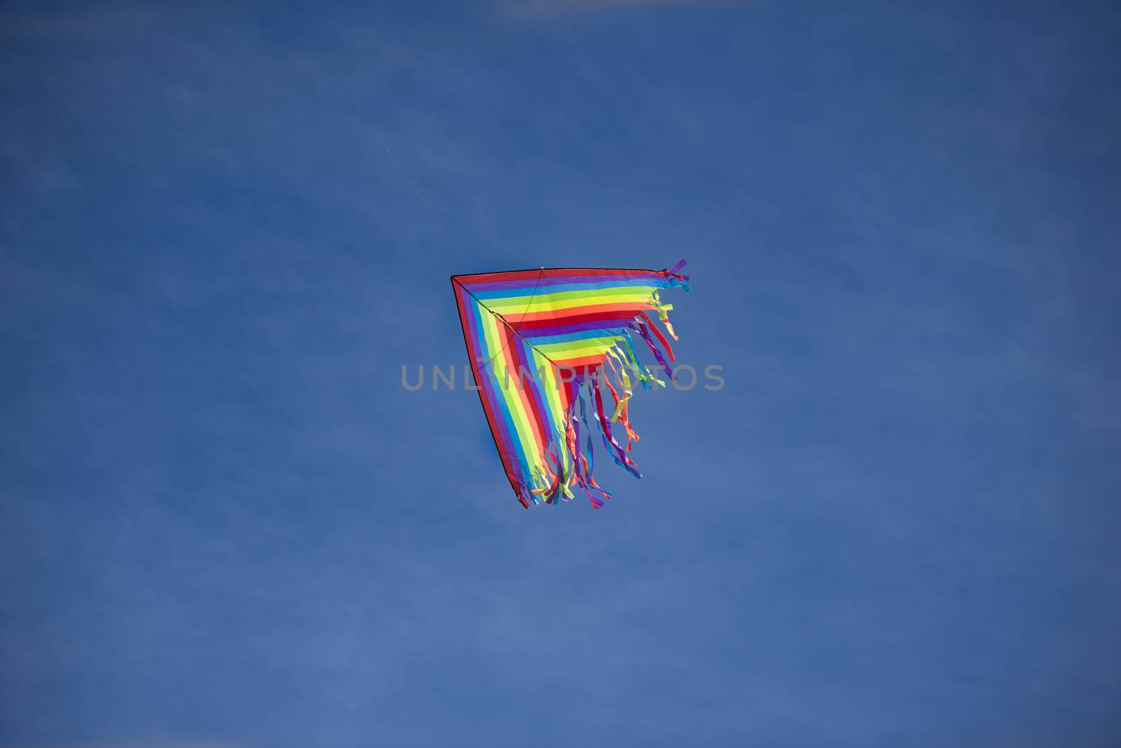 A bright colored kite soaring high in the blue sky