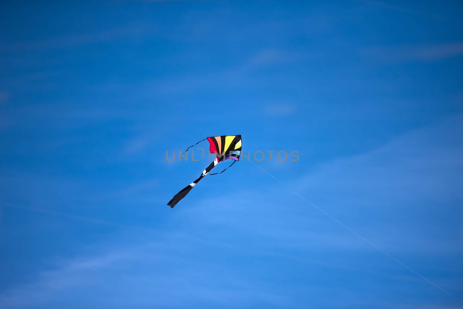 A bright colored kite soaring high in the blue sky