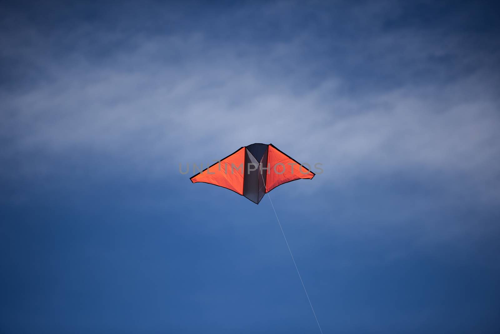 A bright colored kite flying high against a blue sky
