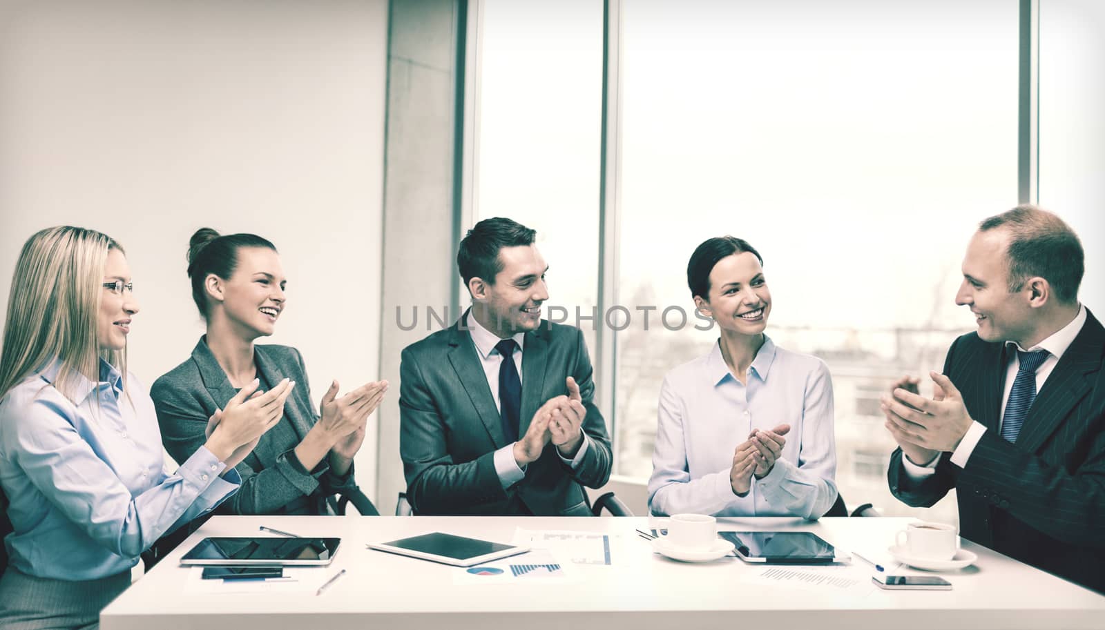 business, technology and office concept - happy business team with laptop computers, documents and coffee clapping hand