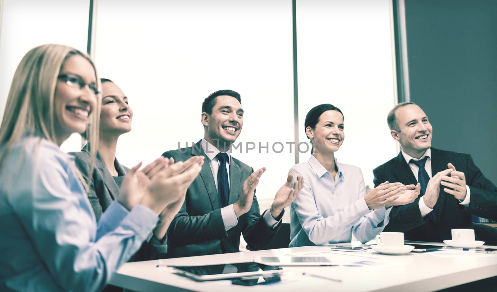 business, technology and office concept - happy business team with laptop computers, documents and coffee clapping hand